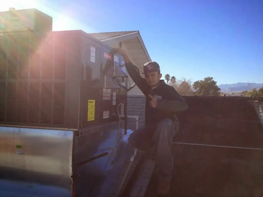 HVAC technician performing AC Tune-Up on a rooftop unit in Davison